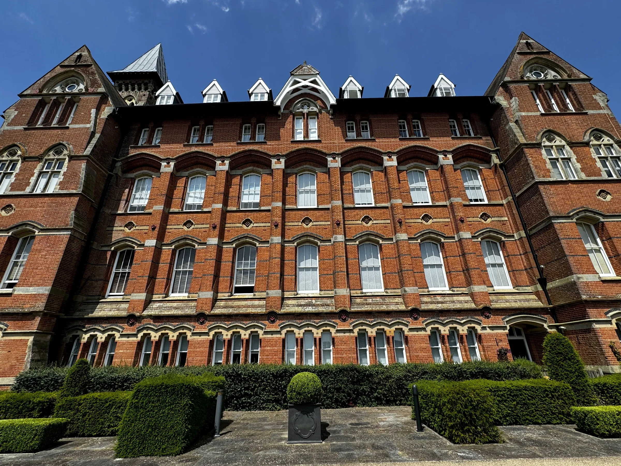 The front of the large Victorian red-brick building and its formal gardens during the works